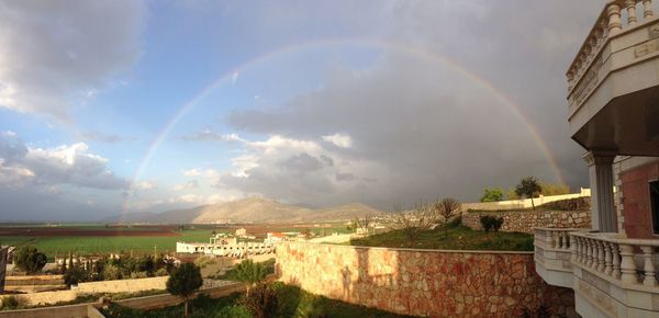 Panoramic view of rainbow over buildings against sky