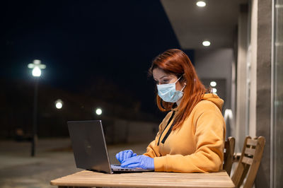 Businesswoman wearing mask using laptop at cafe