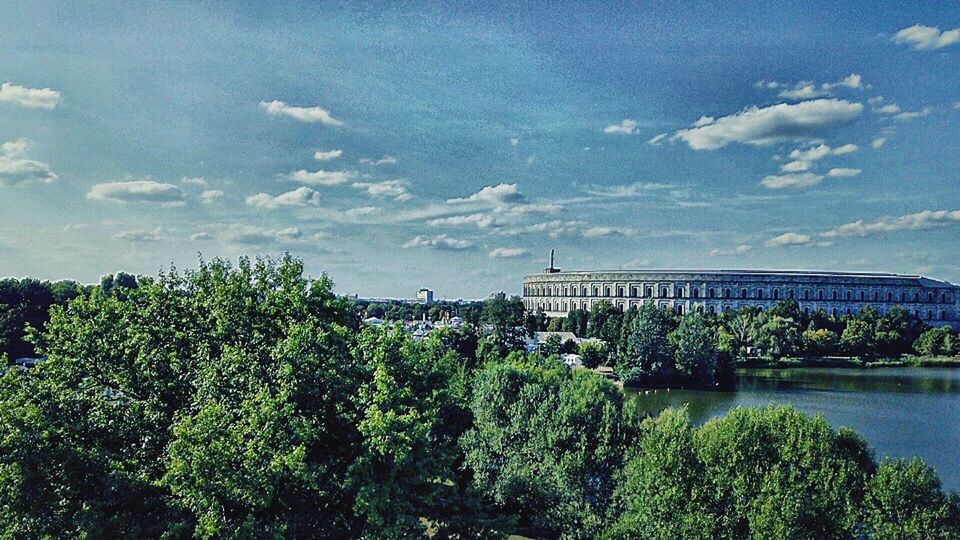 built structure, tree, architecture, plant, sky, bridge, connection, cloud - sky, bridge - man made structure, water, nature, day, transportation, river, no people, growth, building exterior, city, green color, outdoors, arch bridge