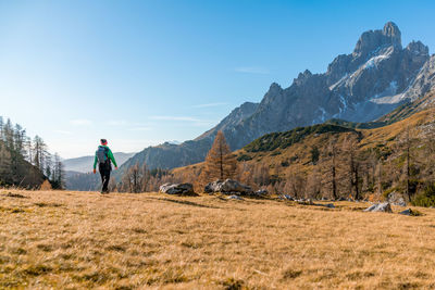 Woman hiking on footpath in alpine landscape in autumn, bischofsmütze, filzmoos, austria