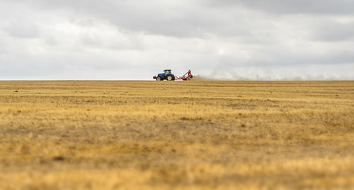 Stormy farmland scenery showing a tractor on a stubble field in hohenlohe