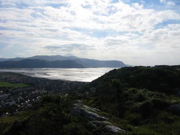 Scenic view of landscape by sea against sky