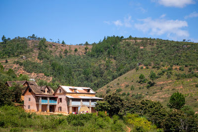 Trees and houses on mountain against sky