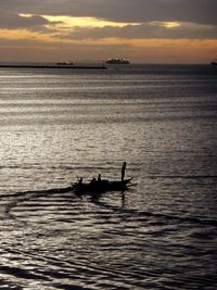 Silhouette man on boat in sea against sky during sunset