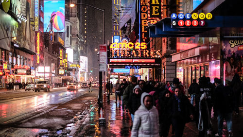 People walking on sidewalk in city during rainy season