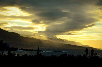 Scenic view of mountains against cloudy sky at sunset