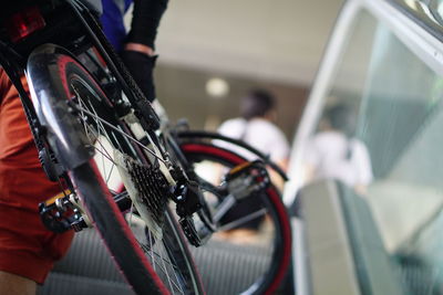 Midsection of man with bicycle on escalator