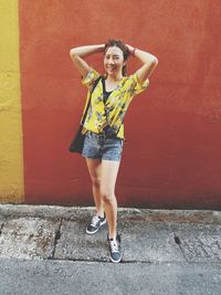 Portrait of a smiling young woman against wall