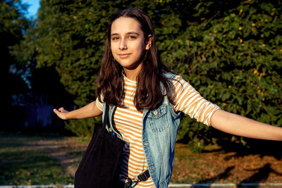 Portrait of young woman standing against trees