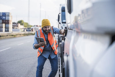 Smiling truck driver examining truck with tablet pc