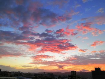 Scenic view of dramatic sky over city during sunset