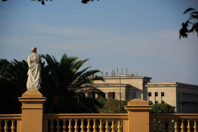 Statue against buildings in city against sky