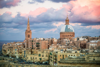 Buildings in city against cloudy sky