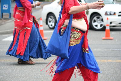 Low section of woman with umbrella on street