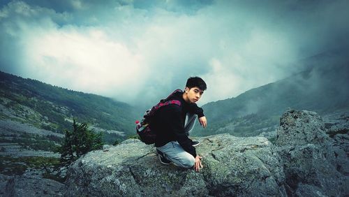 Full length portrait of man on mountains against cloudy sky