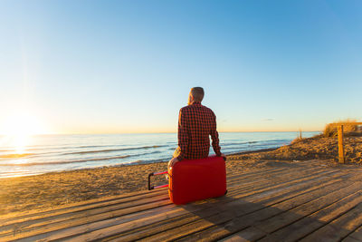 Rear view of man looking at sea against clear sky