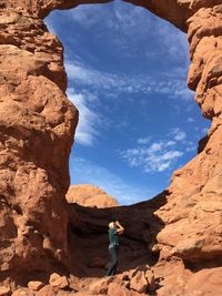 Low angle view of woman standing by rock formation at arches national park