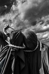 Women tying rope on neck against sky