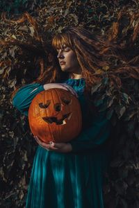 Close-up of woman with pumpkin in background