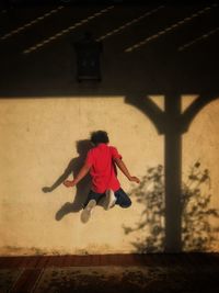 Rear view of man jumping against wall