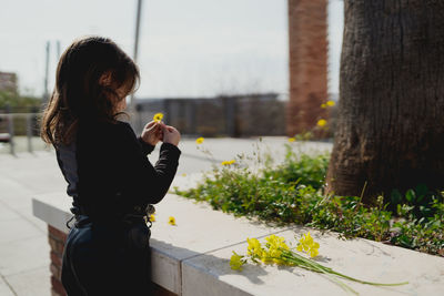 Adorable four-year-old girl looking at the yellow flowers in her hand