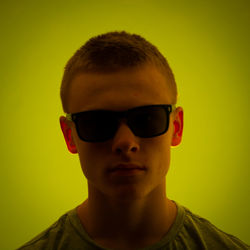 Portrait of young man wearing sunglasses against gray background