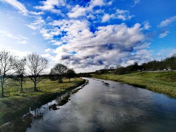 Road by canal against sky