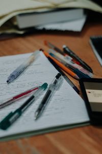 Close-up of pens and book on wooden table