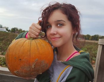 Portrait of smiling girl holding pumpkin against sky