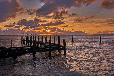 Pier on sea against sky during sunset