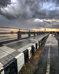 Wet footpath against sky during sunset