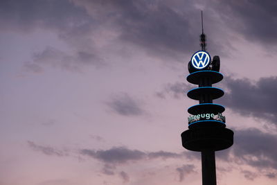 Low angle view of communications tower against cloudy sky