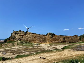 Wind turbines on land against clear sky