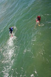 High angle view of people swimming on surfboard in sea