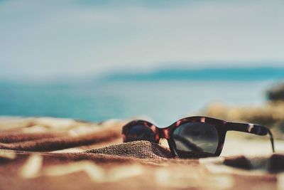 Close-up of sunglasses on beach against sky