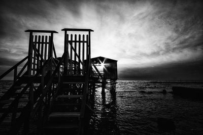 Pier over sea against sky during sunset