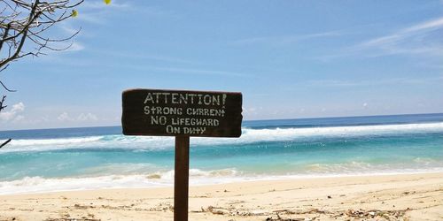 Information sign on beach against sky