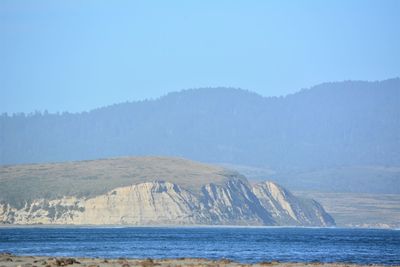 Scenic view of sea and mountains against clear sky