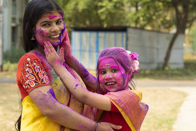 Indian mother and daughter in colorful faces during holi