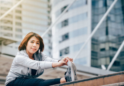 Portrait of young woman exercising against building