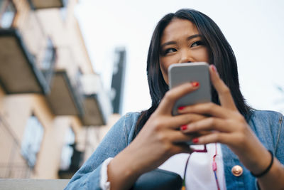 Low angle view of teenage girl holding smart phone