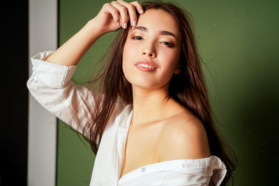 Portrait of beautiful young woman against wall at home