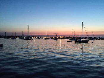 Boats in sea at sunset