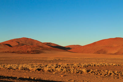 Scenic view of desert against clear blue sky