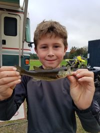 Portrait of smiling boy holding fish on field 