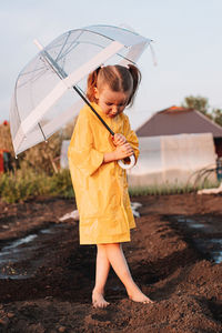 Full length of girl holding umbrella while standing on land