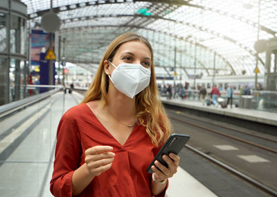 Traveler woman wearing kn95 ffp2 face mask at the airport train station. 