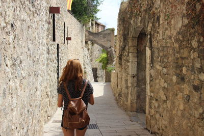 Rear view of woman walking amidst buildings