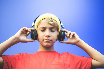 Portrait of boy holding camera against clear blue sky