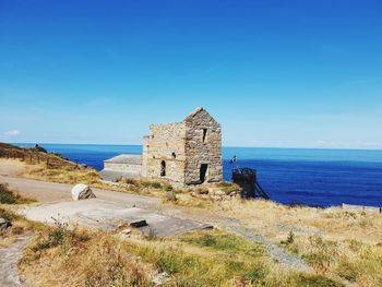 Castle by sea against blue sky